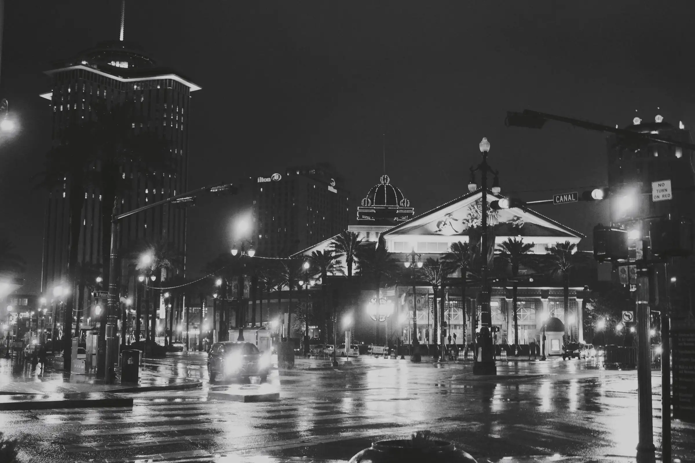 Canal Street in New Orleans at night, in black and white, with streetlights and palm trees