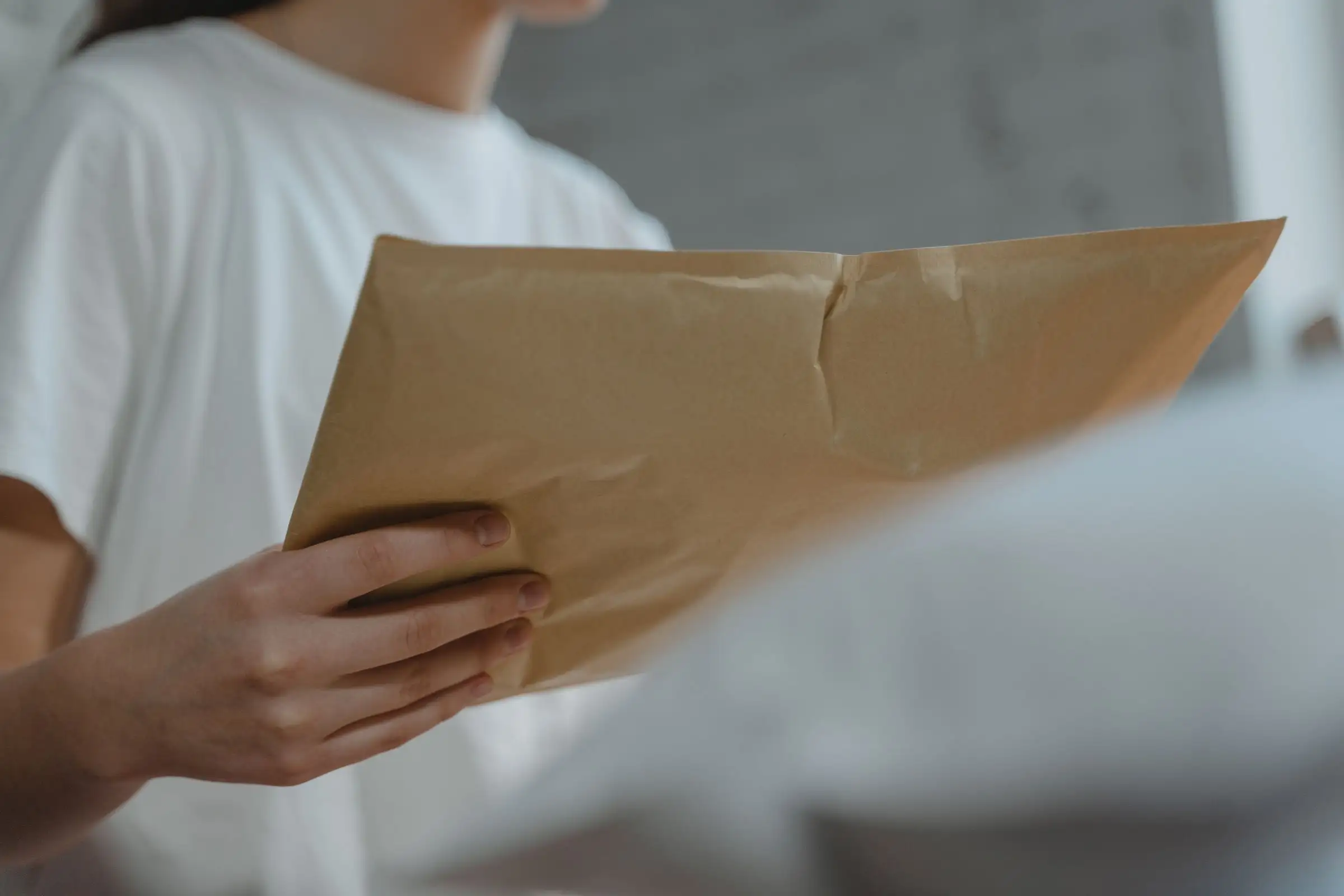 Hands holding a large brown envelope of legal papers
