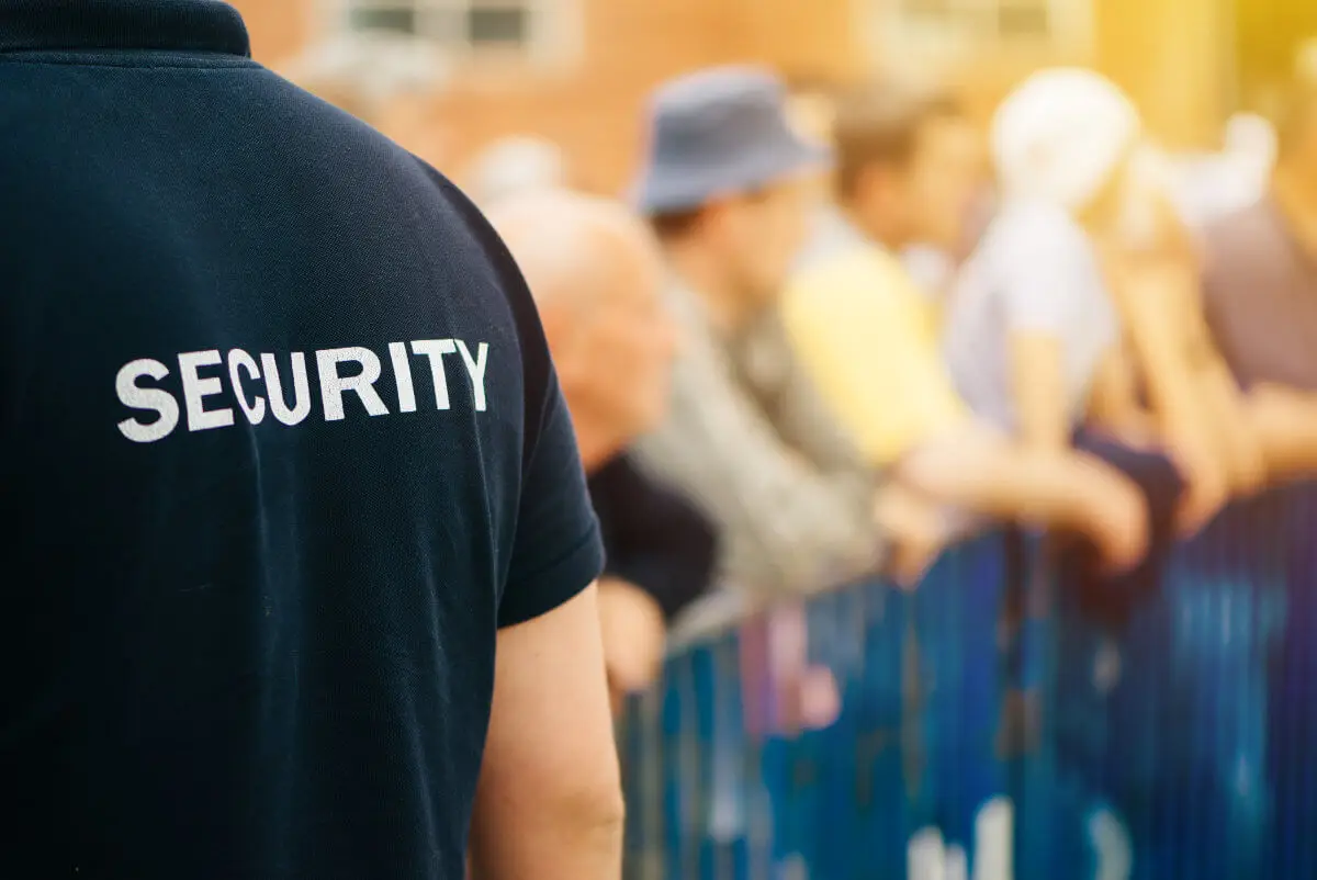 Security officer in a black SECURITY shirt, seen from behind at an event